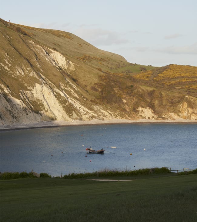 Lulworth Cove view with a fishing boat in the sea