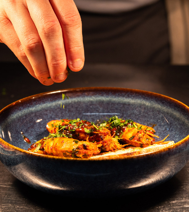 Chef garnishing a freshly prepared restaurant dish at The Lodge at Lulworth, made with Dorset local ingredients.