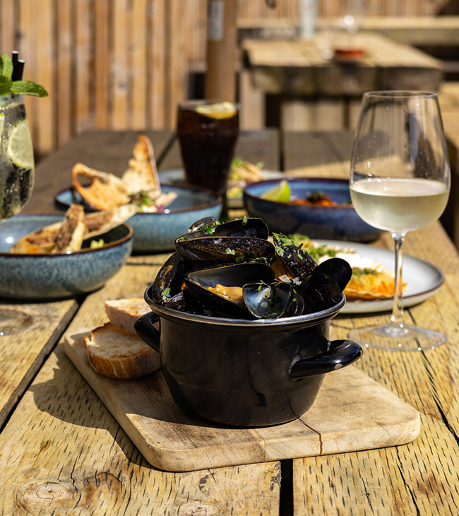 Outdoor lunch on the terrace at the Lodge at Lulworth, serving fresh mussles, locally-caught seafood, and more from the seasonal à la carte menu.